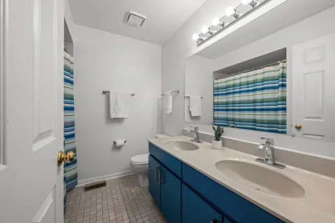 a bathroom with a granite countertop double vanity sink a mirror and a toilet