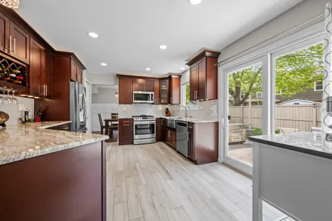 a kitchen with stainless steel appliances granite countertop a stove a sink a refrigerator and a wooden cabinets