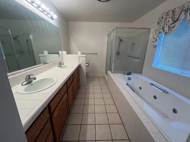 a bathroom with a tub sink vanity granite and mirror