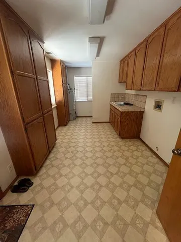 a view of a refrigerator in kitchen and wooden cabinets