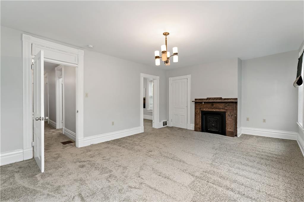5447 Potter Street Pittsburgh, PA 15232 - Photo 15 of 36 an empty room with a fireplace and chandelier