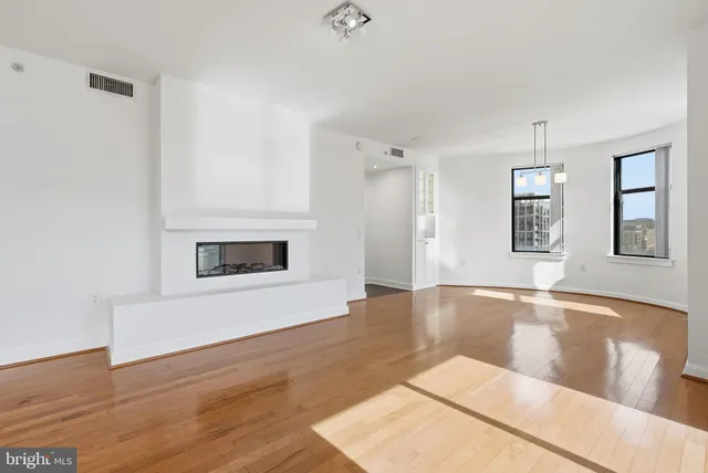 a view of an empty room with wooden floor and a window