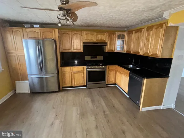 a kitchen with stainless steel appliances granite countertop a refrigerator a sink a stove a microwave and wooden floors