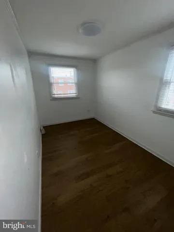 an empty room with wooden floor windows and closet