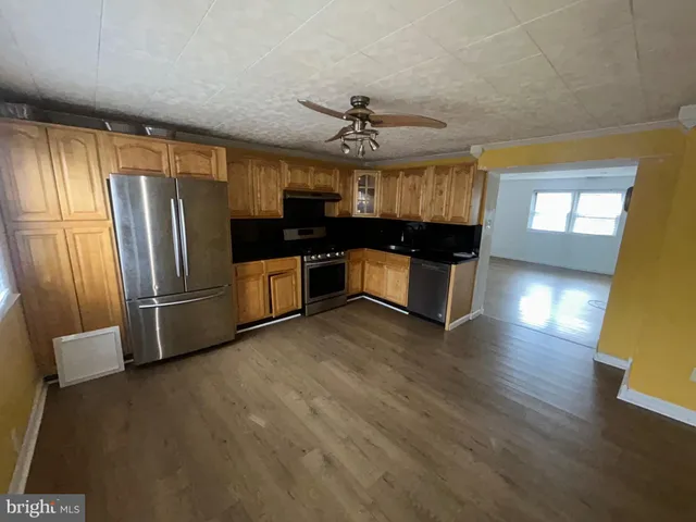 a kitchen with stainless steel appliances granite countertop a refrigerator a sink dishwasher a stove and a dining table with wooden floor