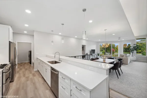 a large kitchen with kitchen island a large counter top space a sink a refrigerator and a counter top space