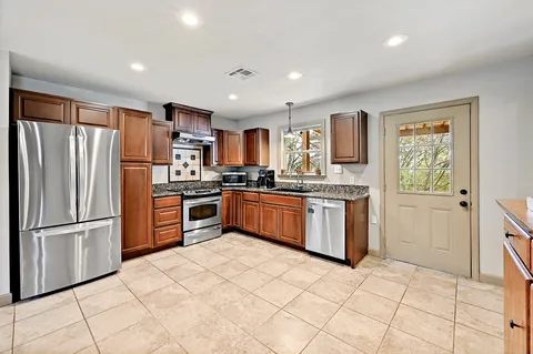 a kitchen with granite countertop a refrigerator and a stove top oven