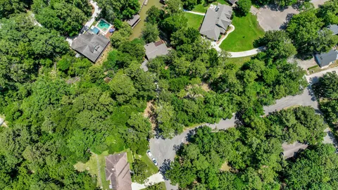 an aerial view of residential house with outdoor space and trees all around