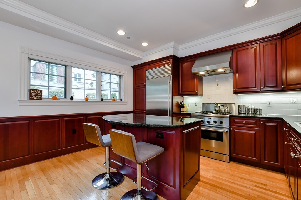 90 Constitution Road, Unit 90 Boston, MA 02129 - Photo 14 of 29 a kitchen with stainless steel appliances granite countertop wooden cabinets a stove a sink and a large window