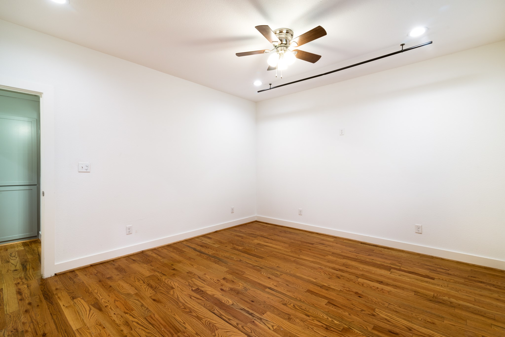 4734 Bell Street Houston, TX 77023 - Photo 13 of 42 an empty room with wooden floor and a ceiling fan