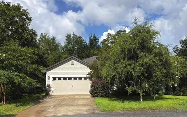 a white house with a small yard and large trees