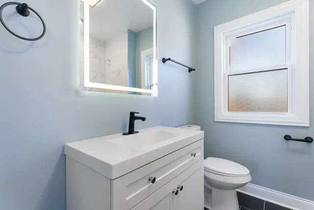 a bathroom with a sink vanity mirror and toilet
