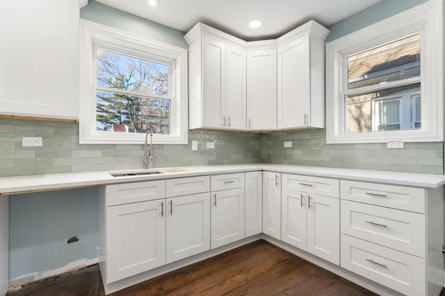 a kitchen with white cabinets and sink