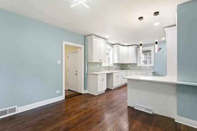 a large kitchen with a dishwasher and white cabinets with wooden floor