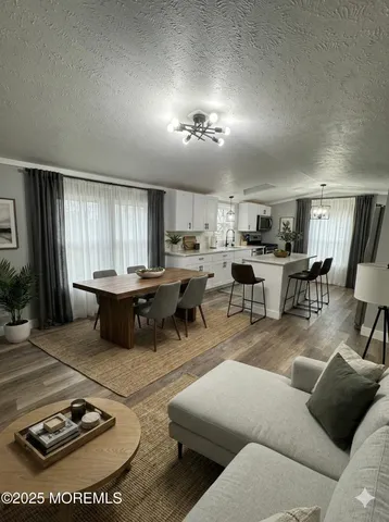 a living room with furniture a wooden floor and kitchen view