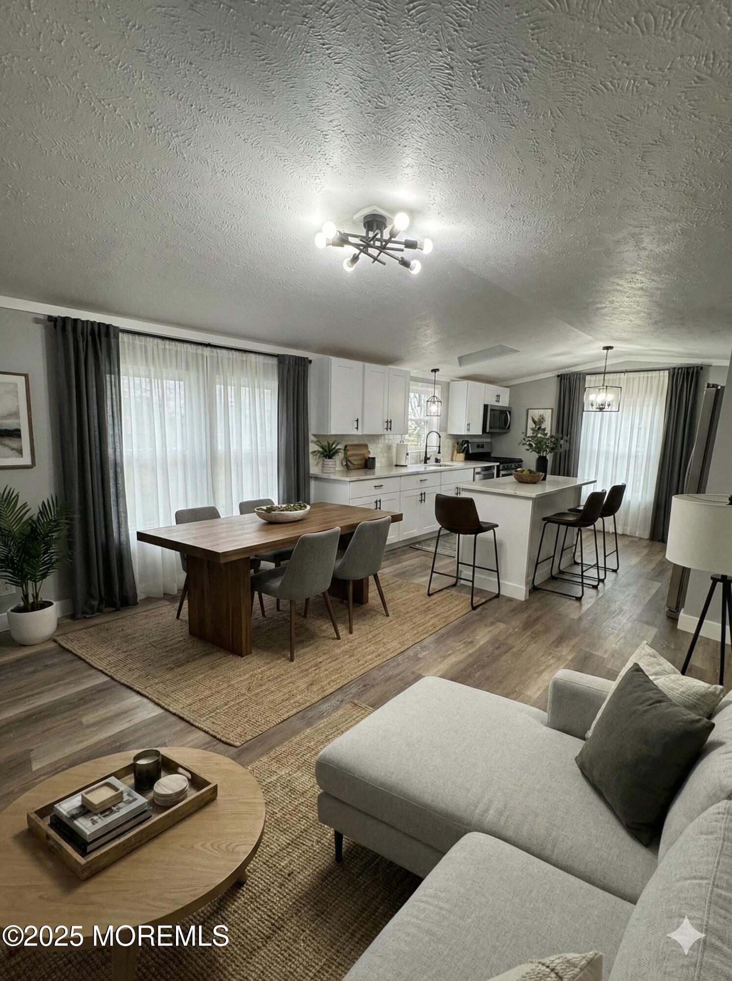 a living room with furniture a wooden floor and kitchen view