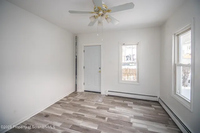 a view of empty room with window and ceiling fan