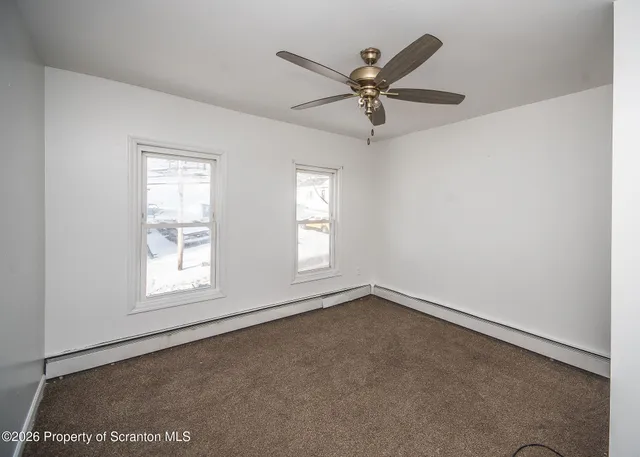 an empty room with windows and fan