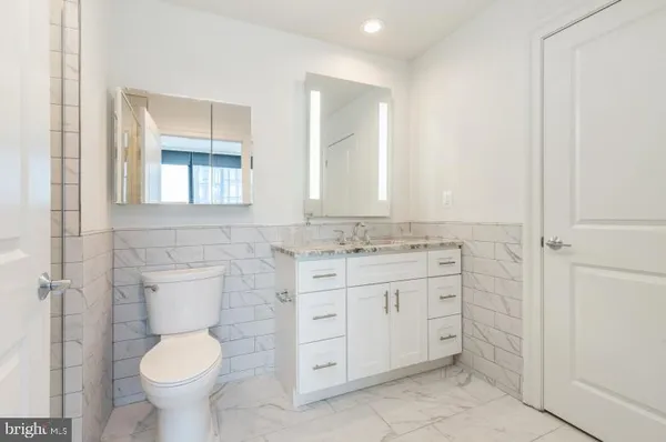 a bathroom with a granite countertop toilet sink and mirror