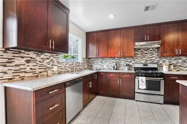 a kitchen with stainless steel appliances granite countertop wooden cabinets a stove top oven a sink and dishwasher