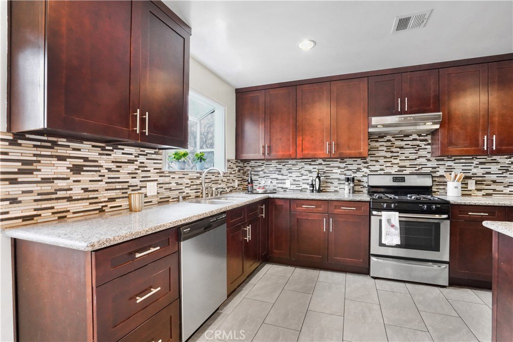 a kitchen with stainless steel appliances granite countertop wooden cabinets a stove top oven a sink and dishwasher
