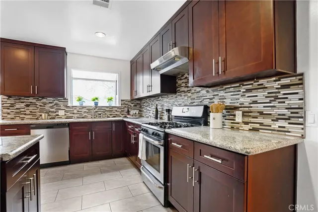 a kitchen with stainless steel appliances granite countertop a sink stove and cabinets