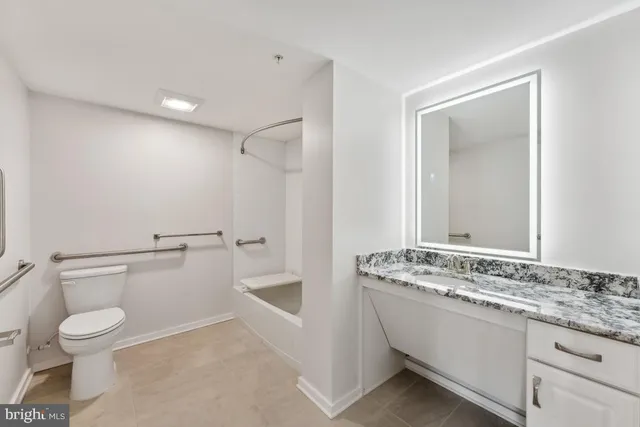 a bathroom with a granite countertop sink a toilet and a mirror