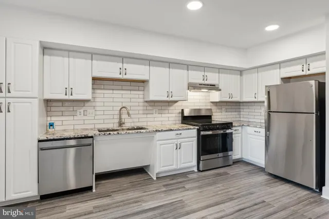 a kitchen with granite countertop a refrigerator stove top oven and sink