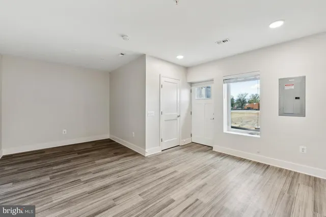 a view of an empty room with wooden floor and a window