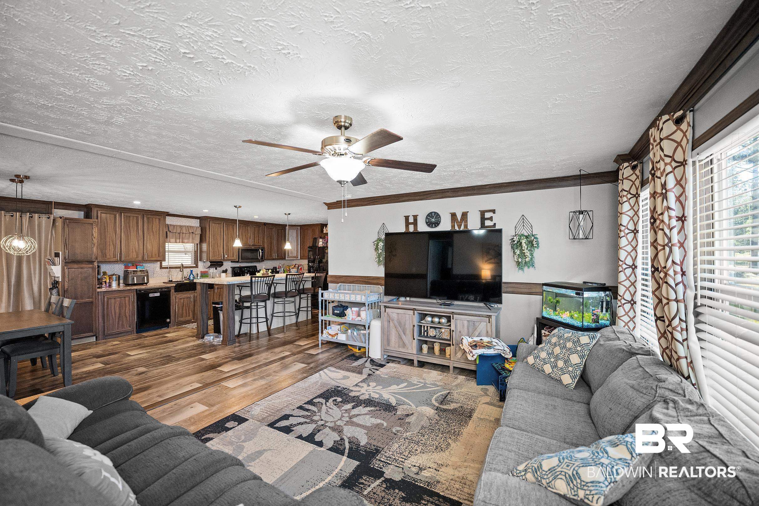 8630 Allison Lane Wilmer, AL 36587 - Photo 5 of 31 Living area featuring dark wood finished floors, a textured ceiling, crown molding, and ceiling fan