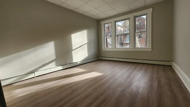 an empty room with wooden floor and windows