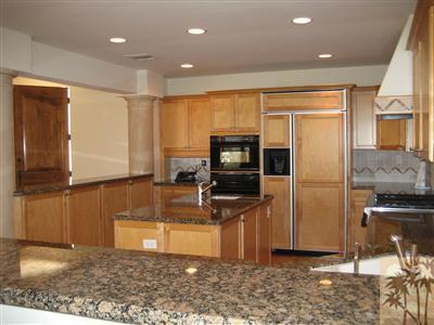 70248 Calico Road Rancho Mirage, CA 92270 - Photo 3 of 9 a kitchen with stainless steel appliances granite countertop a refrigerator a stove and a sink with wooden cabinets