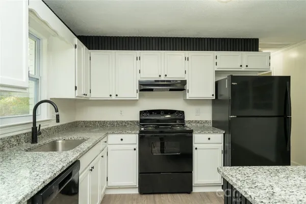 a kitchen with granite countertop a sink stainless steel appliances and white cabinets