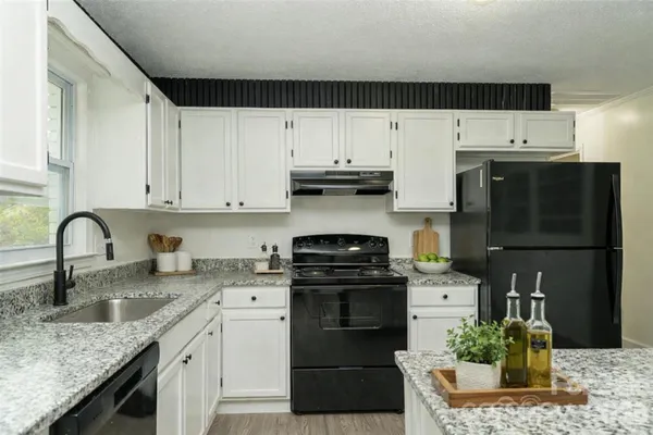 a kitchen with granite countertop a sink and dishwasher a stove a refrigerator with wooden floors