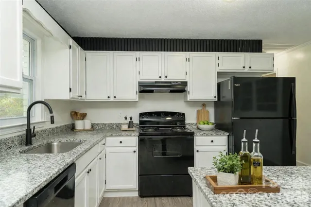 a kitchen with granite countertop a sink and dishwasher a stove a refrigerator with wooden floors