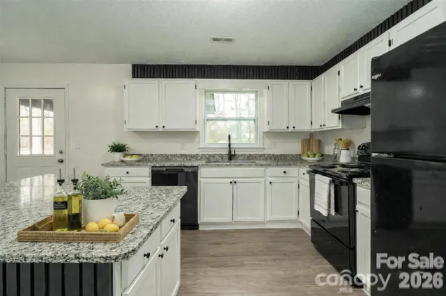 a kitchen with granite countertop stainless steel appliances a refrigerator a stove a sink dishwasher and white cabinets with wooden floor