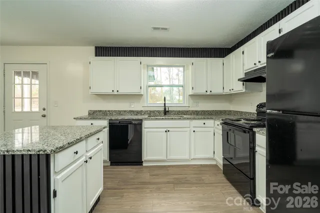 a kitchen with kitchen island granite countertop a stove top oven a sink dishwasher and a refrigerator with wooden floor