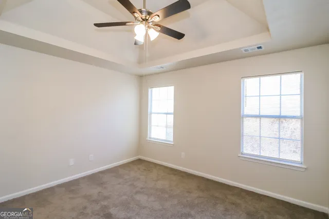 an empty room with windows and fan