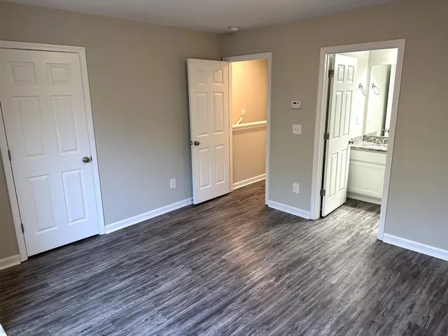 an empty room with wooden floor & closet and windows