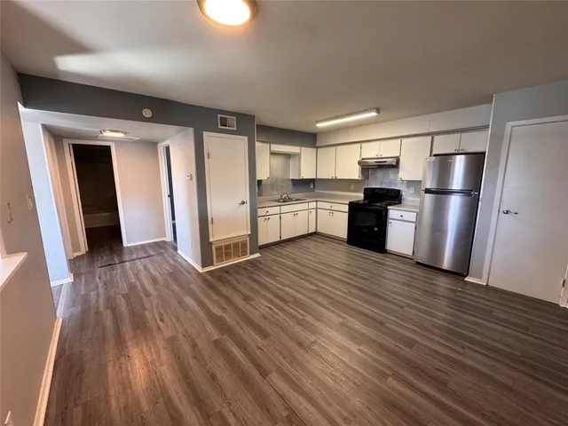 a kitchen with a refrigerator and wooden floor