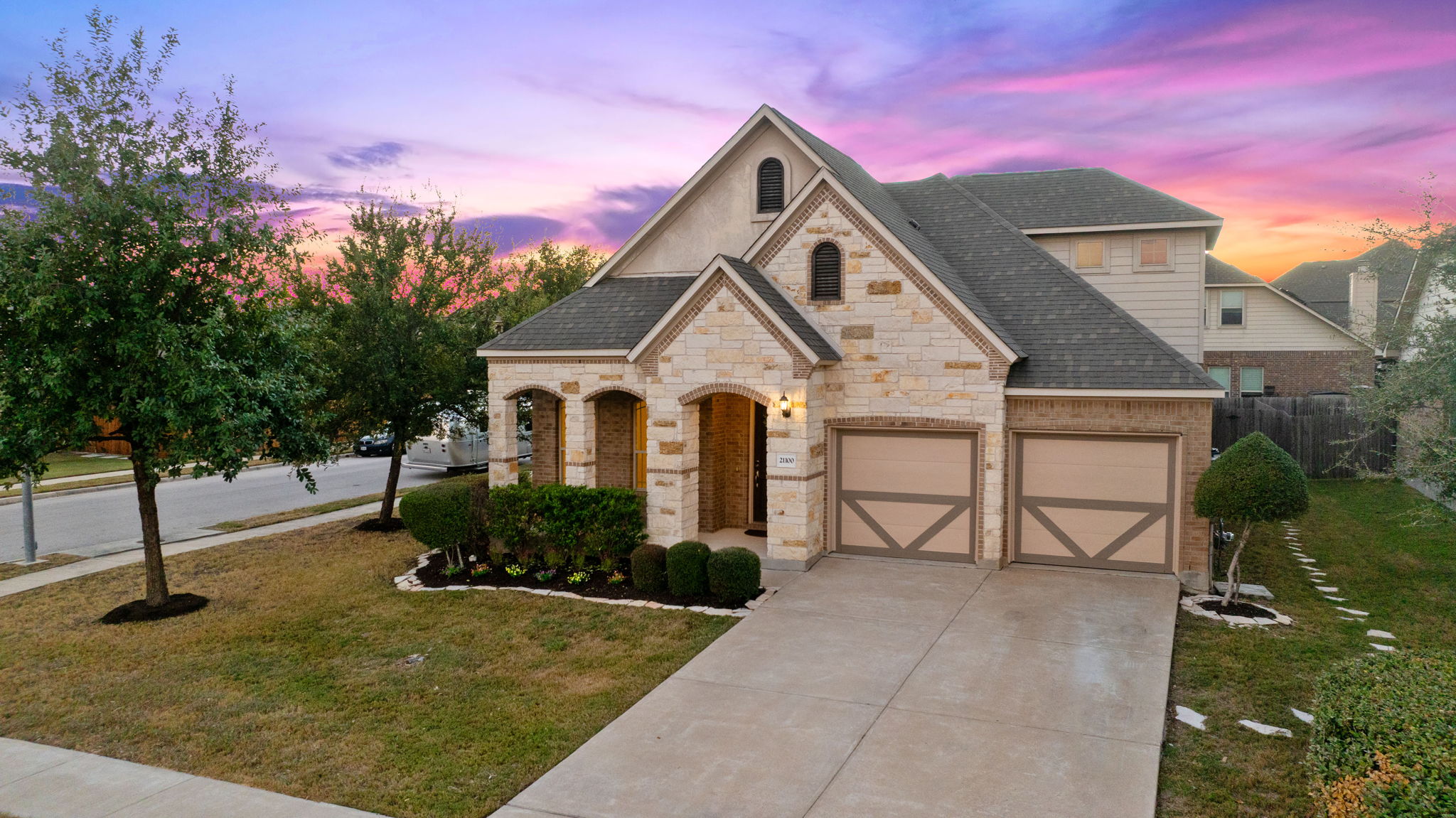 21100 Windmill Ranch Avenue Pflugerville, TX 78660 - Photo 1 of 1 French country style house with stone siding, concrete driveway, a garage, roof with shingles, and brick siding
