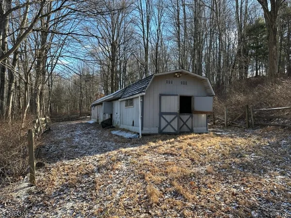 a backyard of a house with table and chairs under an large trees