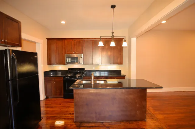 a kitchen with stainless steel appliances granite countertop a refrigerator a sink and a stove