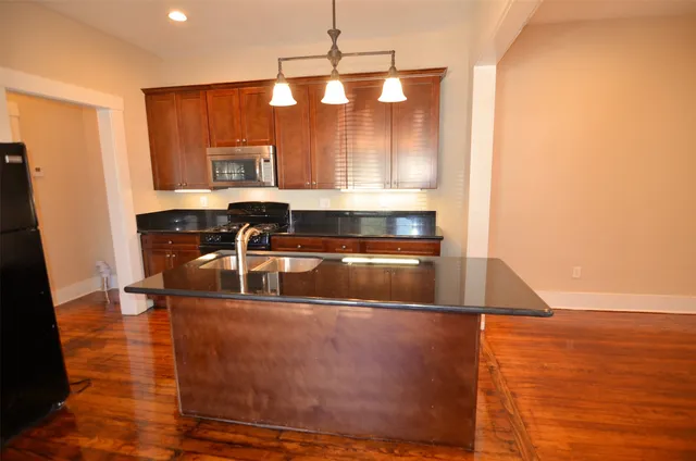 a kitchen with kitchen island granite countertop a sink cabinets and wooden floor