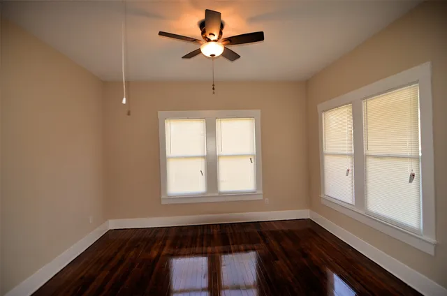 a view of empty room with wooden floor and fan