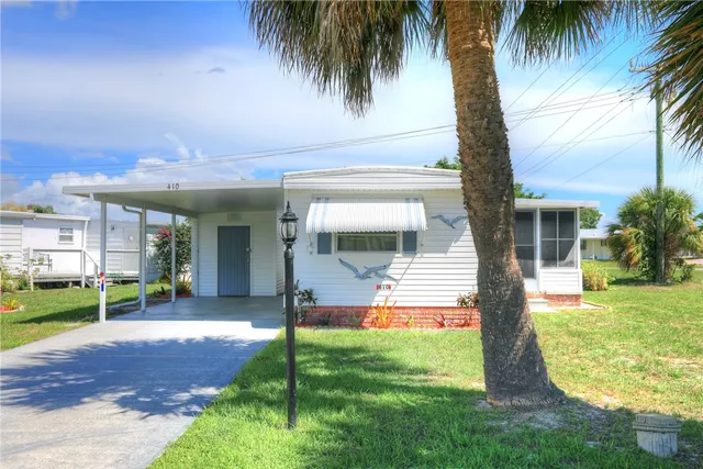 a view of a house with a yard and palm trees