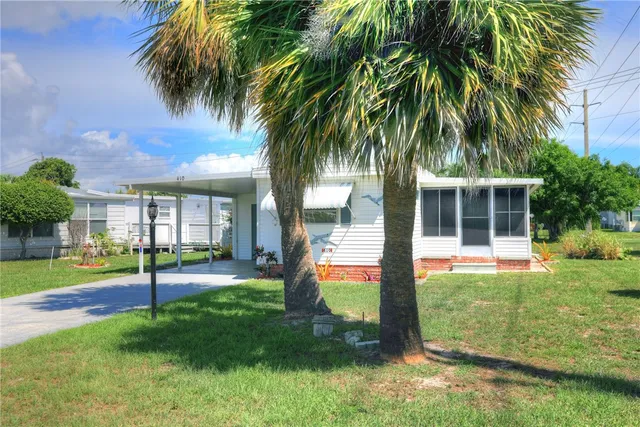 a view of a house with a yard and palm trees