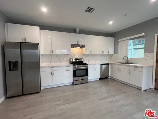 a view of kitchen with stainless steel appliances refrigerator oven stove microwave and cabinets