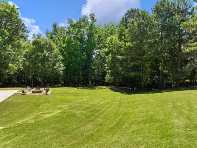 a view of a swimming pool with a yard and large trees