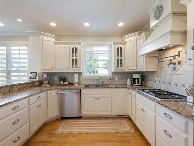 a large kitchen with stainless steel appliances granite countertop a stove a sink and white cabinets